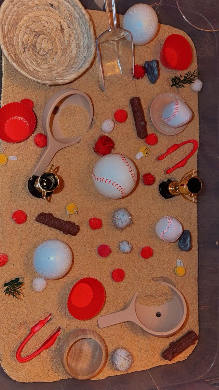 A baseball themed sensory tray with sand, scoops and pom poms