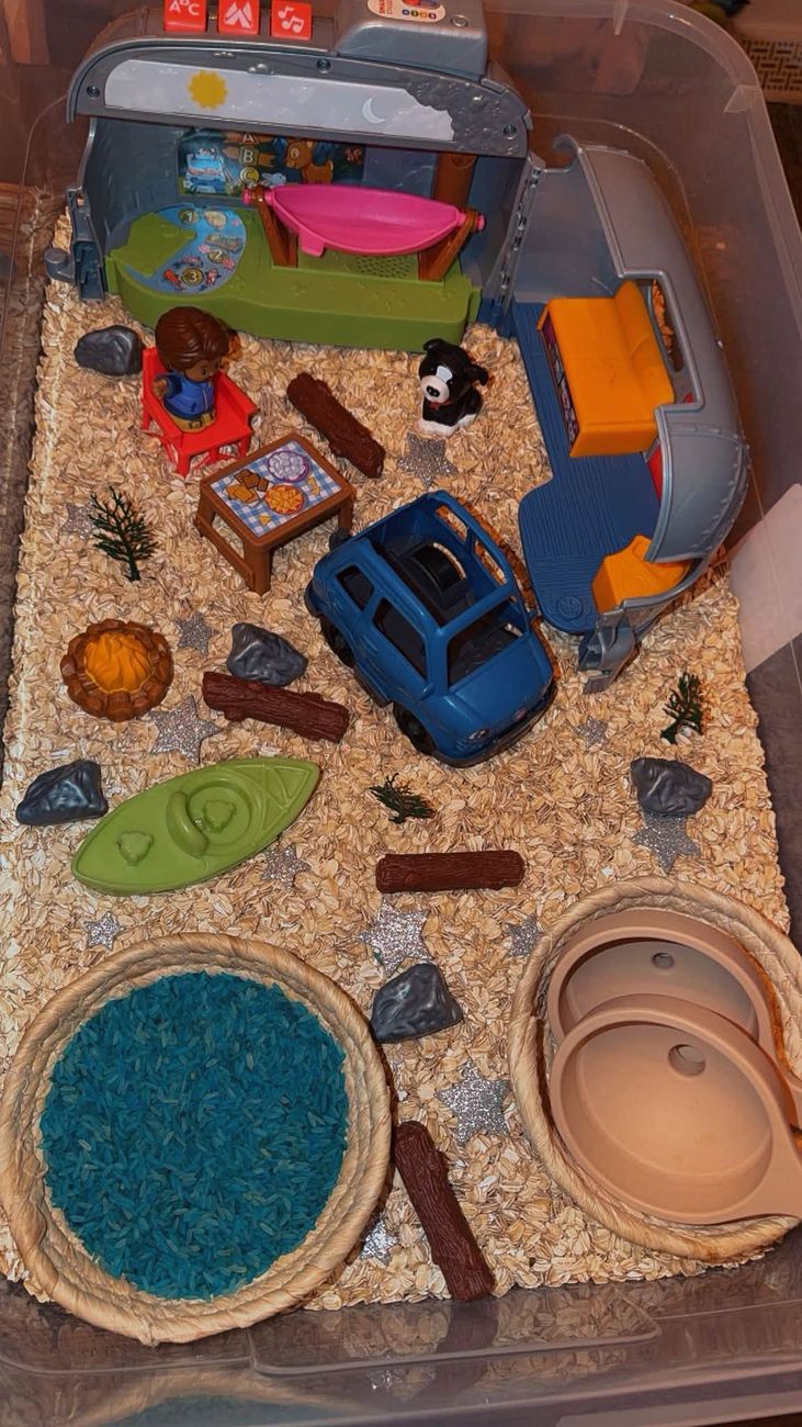 A camping themed sensory tray with oats, a camper van and a kayak